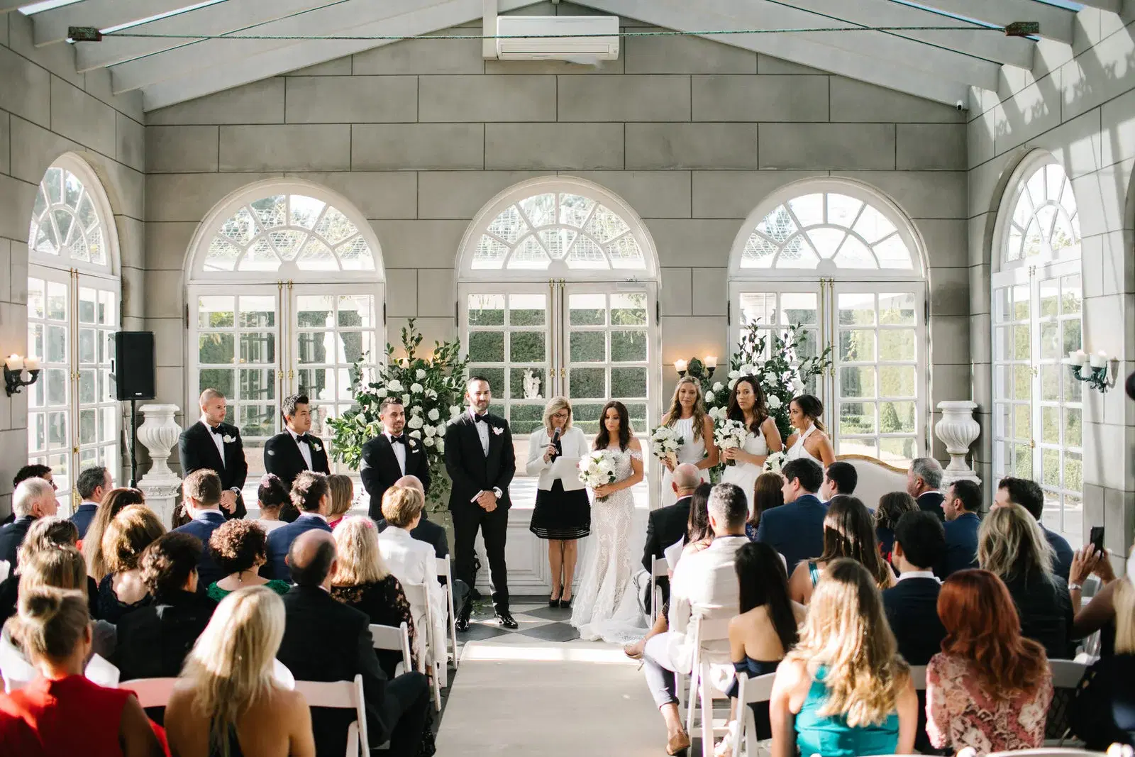 Guests seated inside a light filled wedding venue